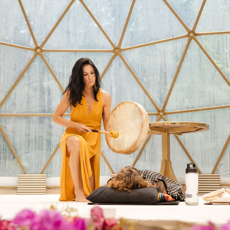 Anya sounding the frame drum beside a resting sister