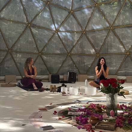 Anya and Bre seated in the dome with red roses and the flower mandala